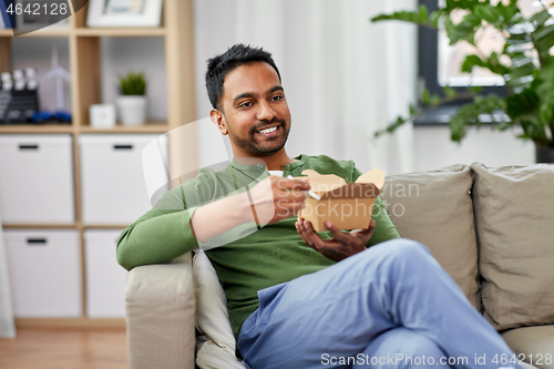 Image of smiling indian man eating takeaway food at home