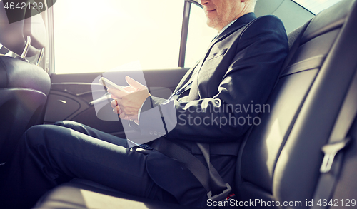 Image of senior businessman texting on smartphone in car