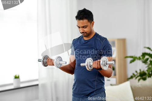 Image of indian man exercising with dumbbells at home