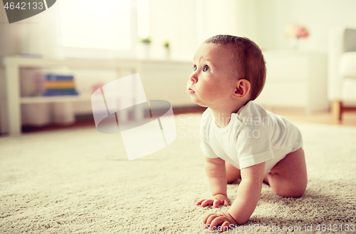 Image of little baby in diaper crawling on floor at home