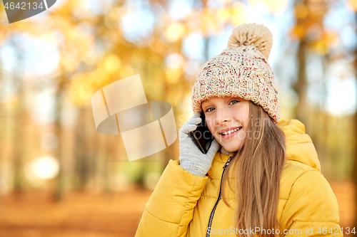 Image of happy girl calling on smartphone at autumn park