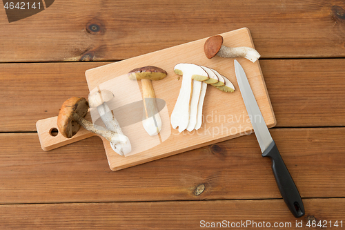 Image of edible mushrooms, kitchen knife and cutting board