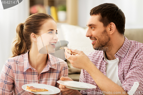 Image of happy couple eating pizza at home