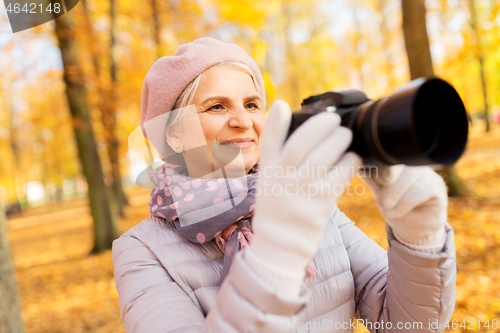 Image of senior woman with photo camera at autumn park