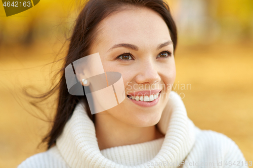 Image of portrait of happy young woman in autumn park