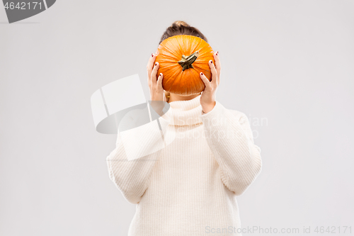 Image of woman holding pumpkin and covering her face