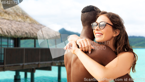 Image of happy mixed race couple hugging on beach