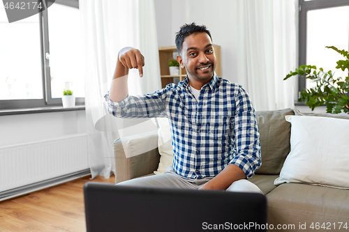 Image of indian male blogger pointing finger down at home