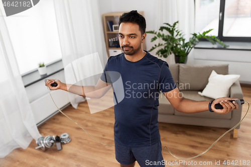 Image of indian man exercising with jump rope at home