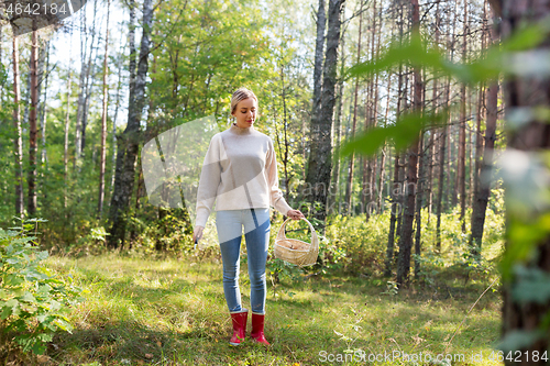 Image of woman with basket picking mushrooms in forest