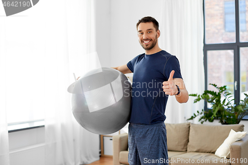 Image of man exercising with fitness ball at home