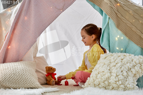 Image of girl playing tea party with teddy in kids tent