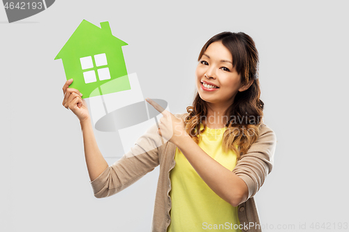 Image of happy asian woman showing green house