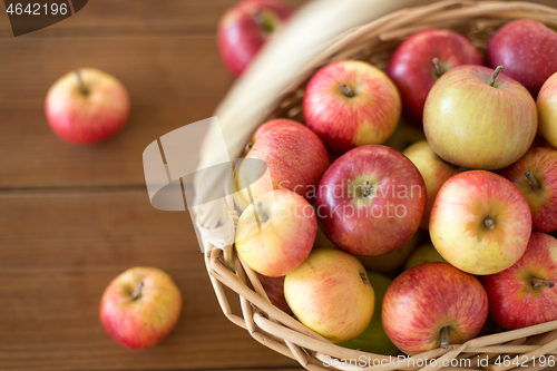 Image of ripe apples in wicker basket on wooden table