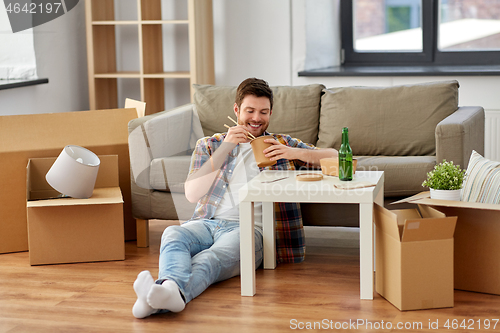 Image of smiling man eating takeaway food at new home