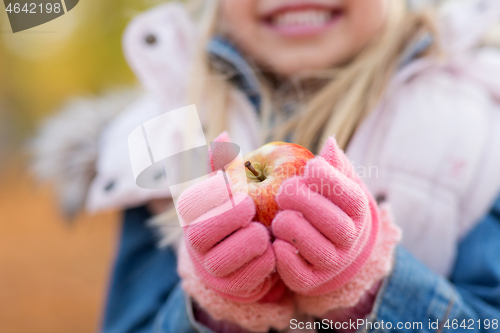 Image of close up of little girl holding apple in autumn