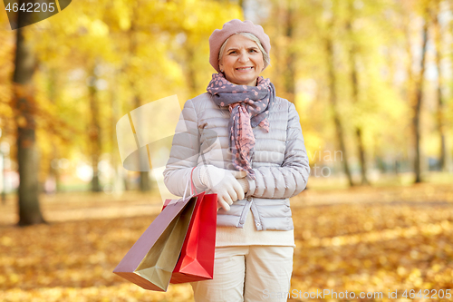 Image of senior woman with shopping bags at autumn park