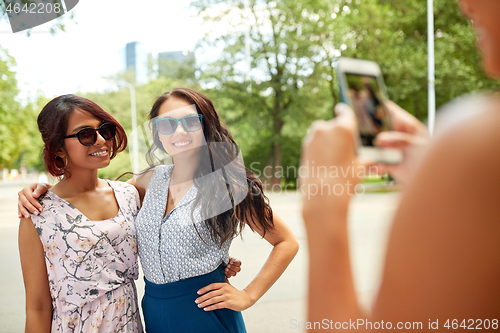 Image of woman photographing her friends in summer park