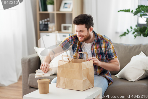 Image of smiling man unpacking takeaway food at home