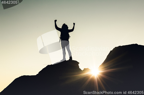 Image of Man with arms raised at sunset