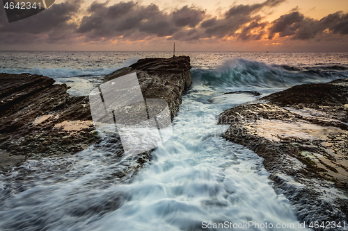 Image of Waves crash as sunrise dawns over the ocean