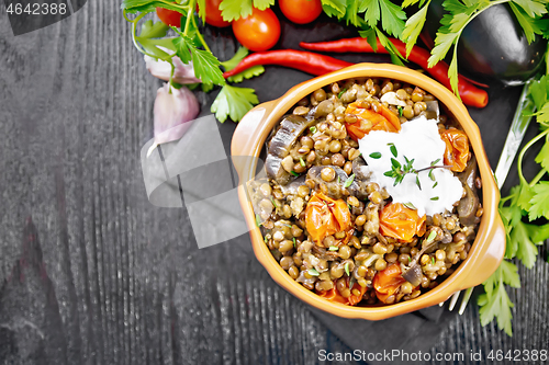 Image of Lentils with eggplant and tomatoes in bowl on dark board top