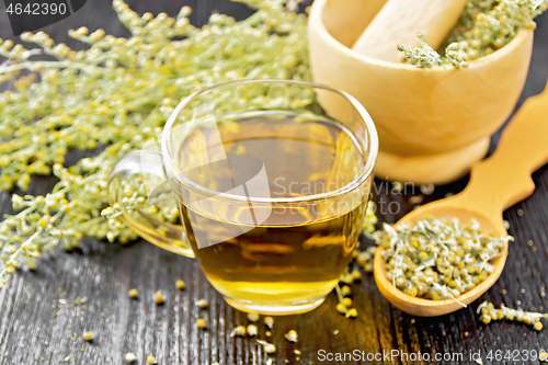 Image of Tea of gray wormwood in glass cup with mortar on black board