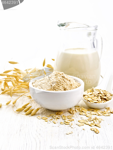 Image of Flour oat in bowl with milk on wooden board