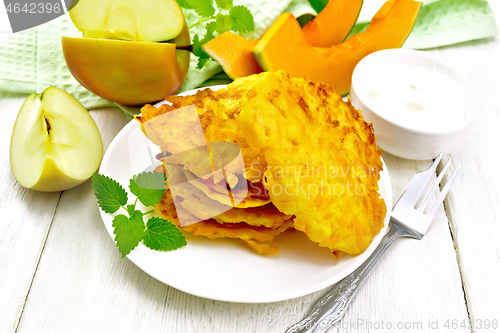 Image of Pancakes of pumpkin with apple in plate on wooden board