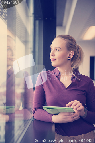 Image of blonde businesswoman working on tablet at office