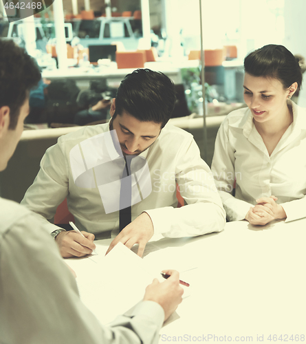 Image of young couple signing contract documents on partners back