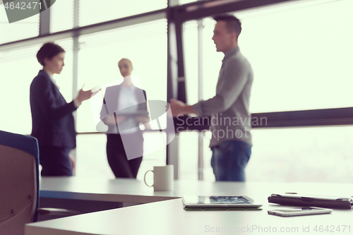 Image of close up of tablet, business people on meeting in background