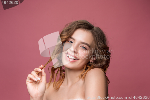 Image of Nice young smiling woman with long wavy silky hair, natural make up looking at camera
