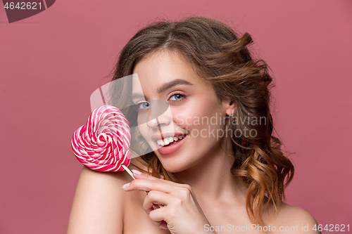 Image of beauty portrait of a cute girl in act to eat a candy