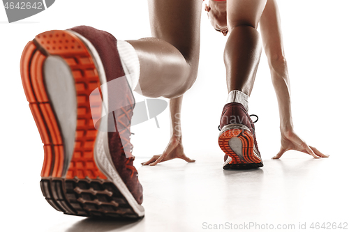 Image of Portrait of young sporty woman at starting block of race isolated over white background