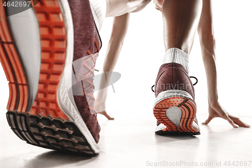 Image of Portrait of young sporty woman at starting block of race isolated over white background