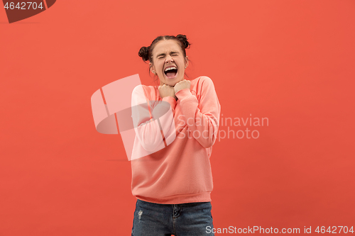 Image of The happy woman standing and smiling against coral background.