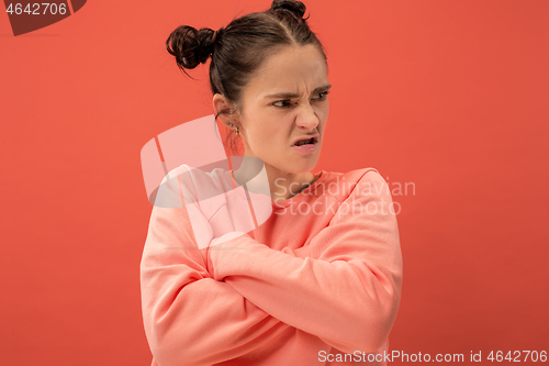 Image of Portrait of an angry woman looking at camera isolated on a coral background