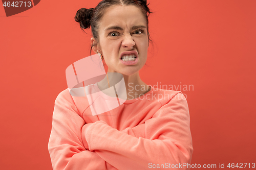 Image of Portrait of an angry woman looking at camera isolated on a coral background