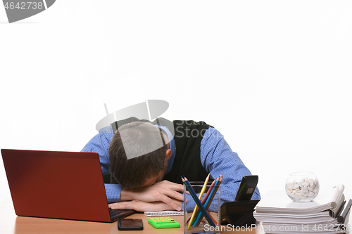 Image of sleeping employee in the office at the table put his head on his hands