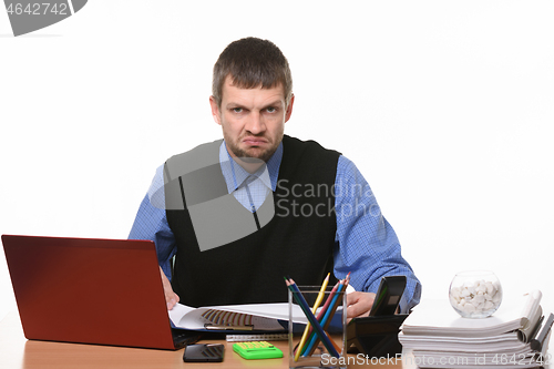 Image of disgruntled office worker sits in his workplace