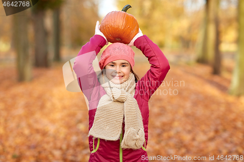 Image of happy girl with pumpkin at autumn park