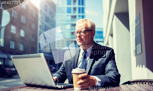 Image of senior businessman with laptop drinking coffee