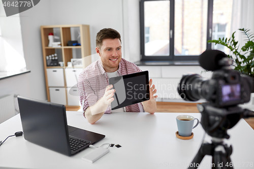 Image of male blogger with tablet pc videoblogging at home