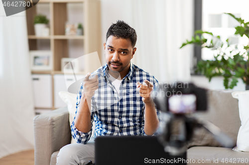 Image of male blogger with camera videoblogging at home