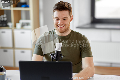 Image of man with laptop and microphone at home office