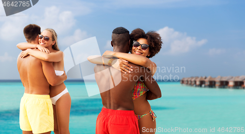 Image of happy friends or couples hugging on summer beach