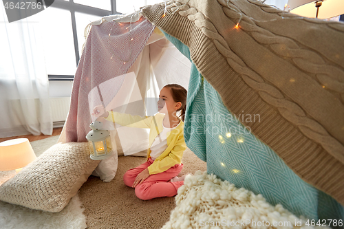 Image of little girl with lantern in kids tent at home