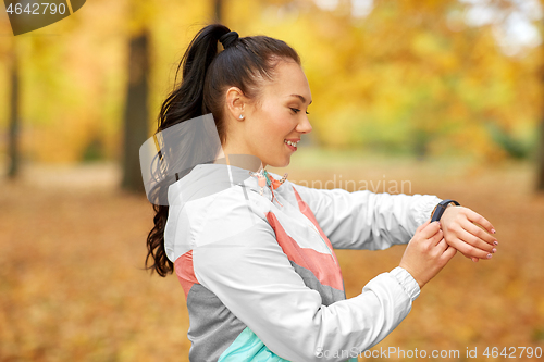 Image of woman looking at fitness tracker in autumn park