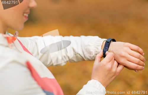 Image of woman with fitness tracker outdoors in autumn